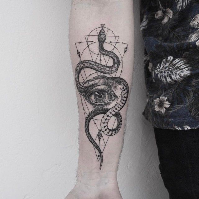 Forearm tattoo featuring an intricate snake wrapped around a geometric eye design on a person in a floral shirt.