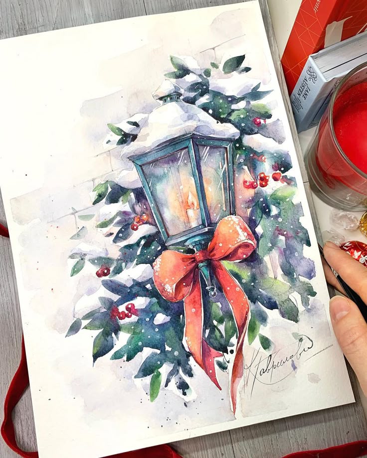 Watercolor painting of a festive lantern with glowing light, adorned with snowy foliage, red berries, and an orange ribbon, evoking holiday spirit.
