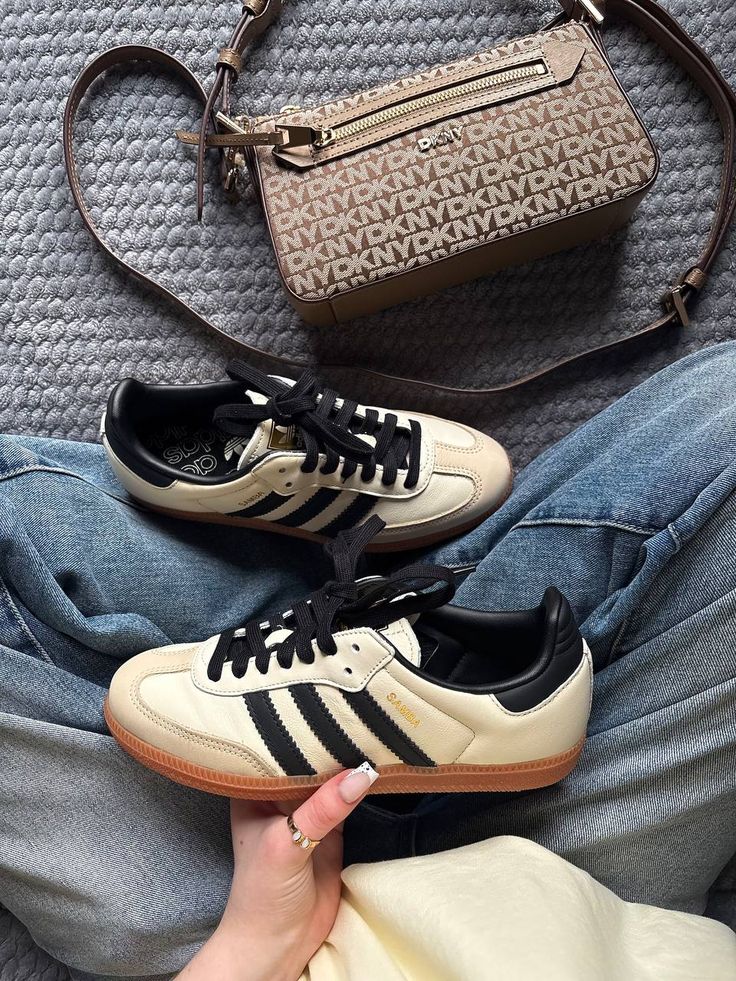 Casual outfit with stylish sneakers and a designer handbag on a gray textured background. Fashion accessories and denim jeans.