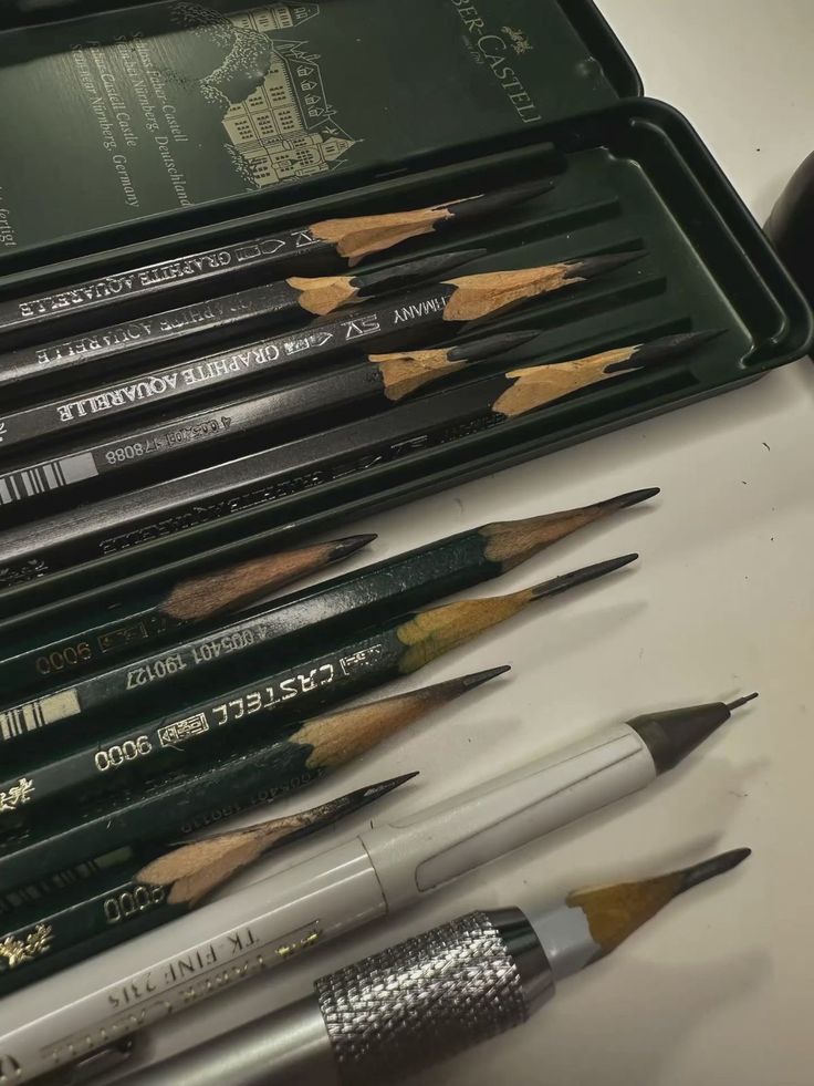 caspian deveraux _ oleander _ scarlett drake A set of Faber-Castell graphic pencils and mechanical pencils arranged on a desk for drawing or sketching. | Sky Rye Design A set of Faber-Castell graphic pencils and mechanical pencils arranged on a desk for drawing or sketching.