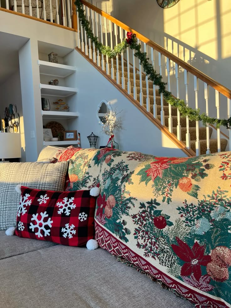 christmas living room decor Cozy living room decor with festive cushions and a holiday-themed throw on the couch, beside a staircase adorned with garland. | Sky Rye Design Cozy living room decor with festive cushions and a holiday-themed throw on the couch, beside a staircase adorned with garland.