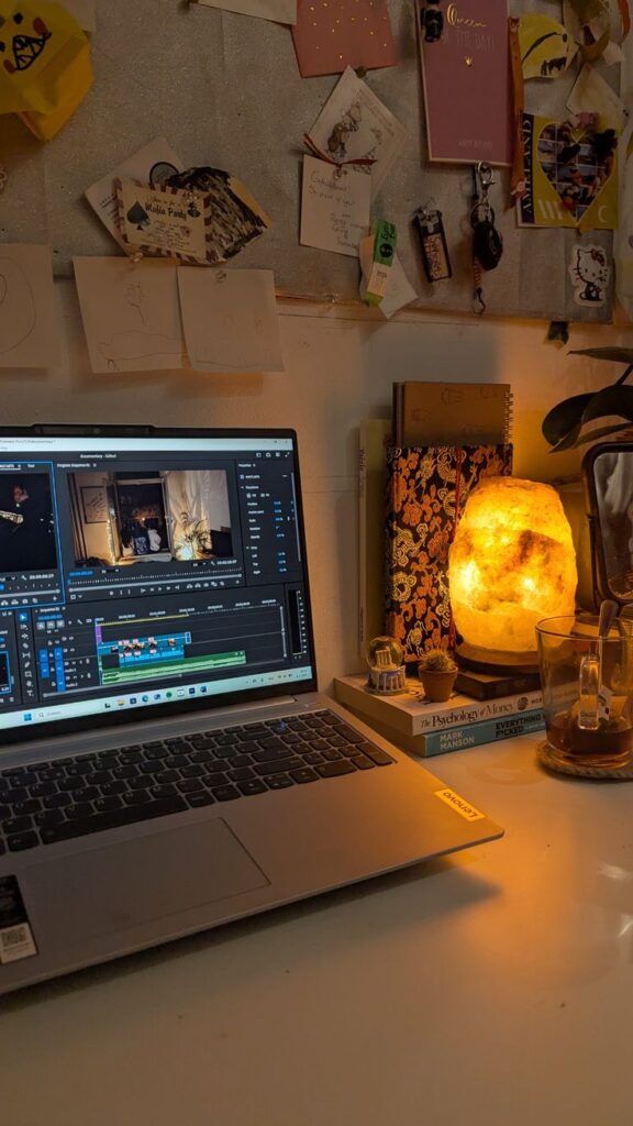 college mood Cozy workspace with laptop showing video editing software, salt lamp, books, and wall decorations. | Sky Rye Design Cozy workspace with laptop showing video editing software, salt lamp, books, and wall decorations.