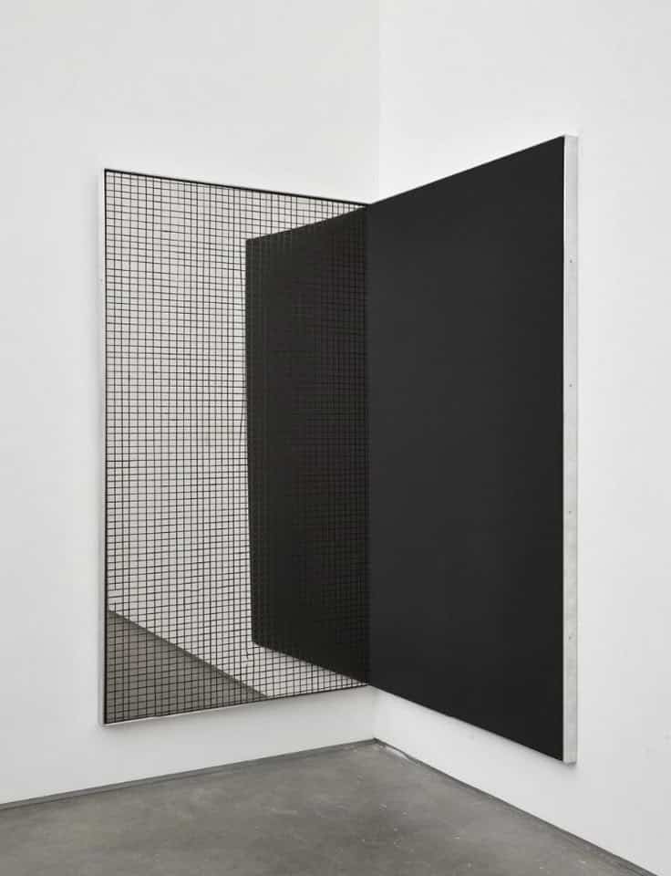 Abstract black and grid art installation in a minimalistic gallery corner, featuring sharp lines and geometric forms.