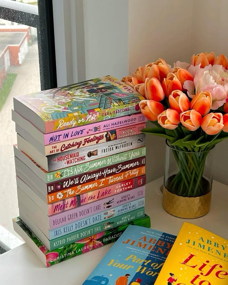 d38e3c68-8684-4952-8731-434c007808fc Stack of colorful books next to a vase of orange tulips on a windowsill, creating a cozy reading nook atmosphere. | Sky Rye Design Stack of colorful books next to a vase of orange tulips on a windowsill, creating a cozy reading nook atmosphere.