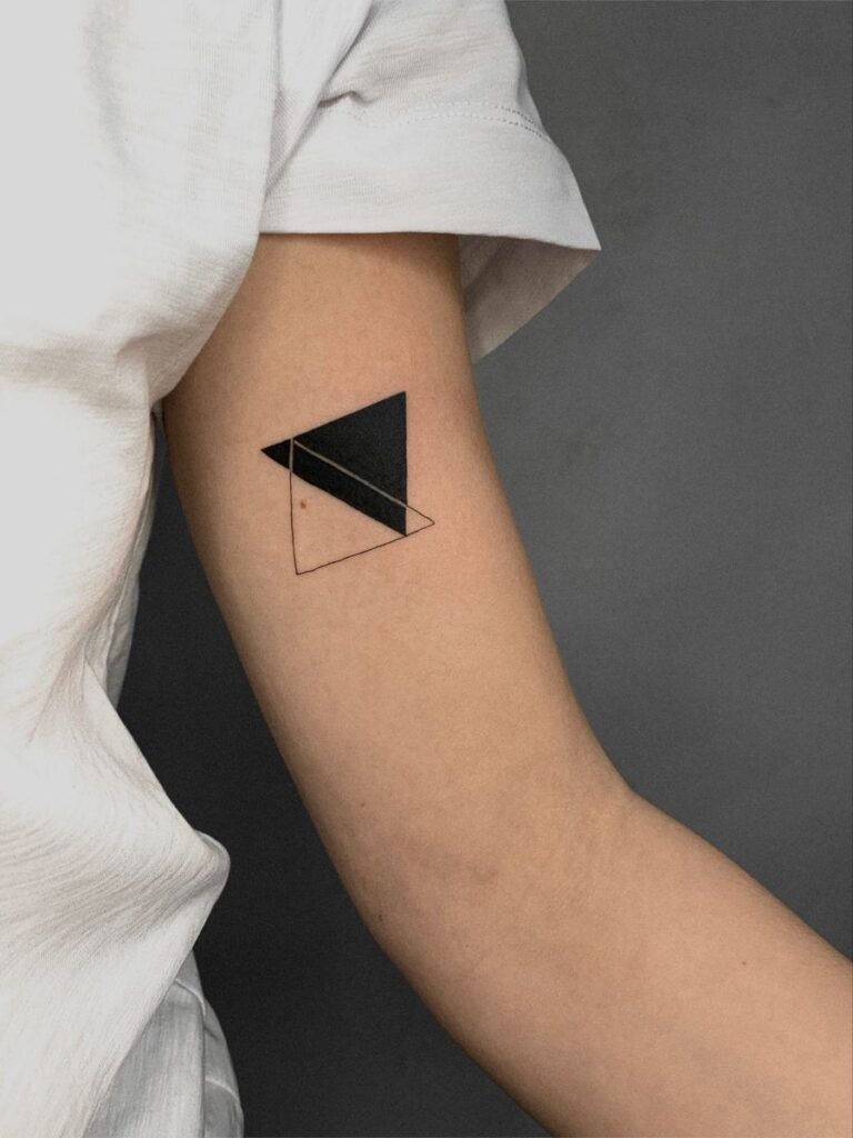 d47e51f6f9dae691ee6bb1450d8c08e0 Minimalist geometric tattoo on an upper arm, featuring black and outlined triangles on light skin. | Sky Rye Design Minimalist geometric tattoo on an upper arm, featuring black and outlined triangles on light skin.