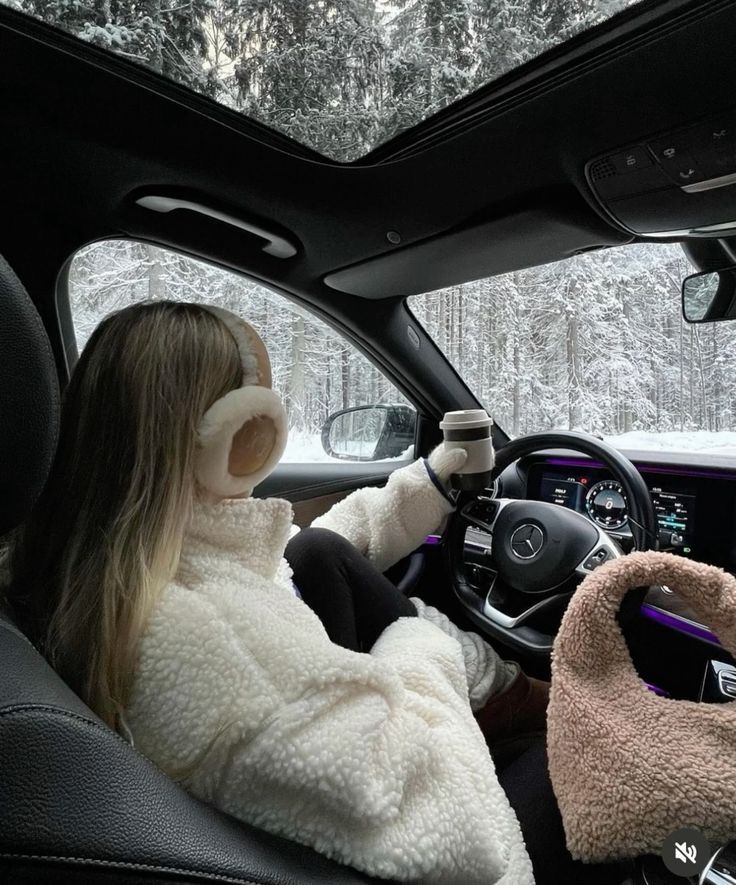 daca00963827c212965a9db4dab0c100 Woman in a cozy fleece jacket driving a car through a snowy forest, holding a coffee cup, with earmuffs and a fluffy bag in view. | Sky Rye Design Woman in a cozy fleece jacket driving a car through a snowy forest, holding a coffee cup, with earmuffs and a fluffy bag in view.