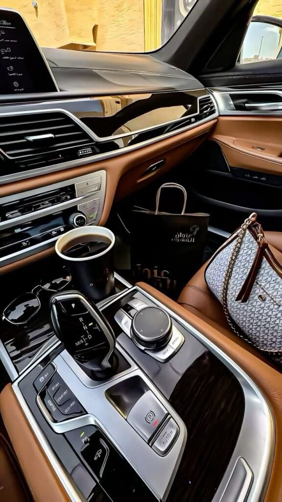 Luxurious car interior with leather seats, sleek dashboard, and coffee cup in holder. Sophisticated design and modern tech features.