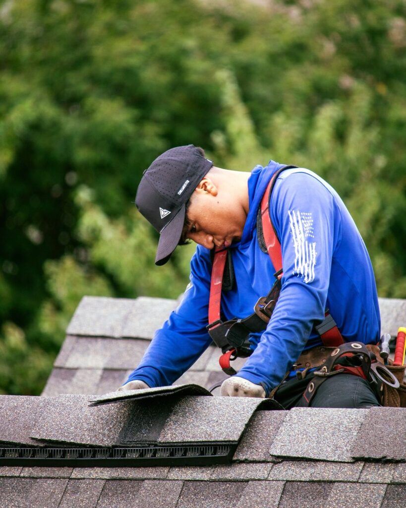 ec8794e8b8d639375263a3930089e013 Roofer in safety gear installing shingles on a roof, trees in the background. | Sky Rye Design Roofer in safety gear installing shingles on a roof, trees in the background.