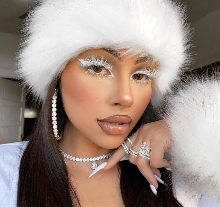 Woman in white fur hat with glamorous makeup, diamond jewelry, and long nails. Elegant winter fashion look with dramatic lashes.