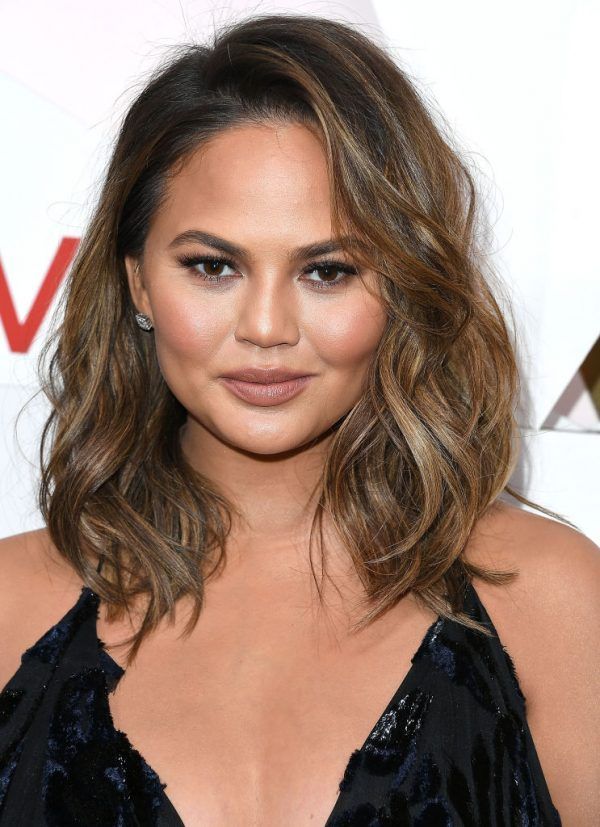 Portrait of a woman with wavy brown hair wearing a black dress at a formal event.