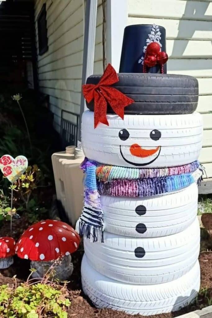 f595737134236607c0ad98c7c86cc2c7 Creative snowman made from stacked tires, decorated with a scarf, hat, and a red bow, next to garden mushrooms. | Sky Rye Design Creative snowman made from stacked tires, decorated with a scarf, hat, and a red bow, next to garden mushrooms.
