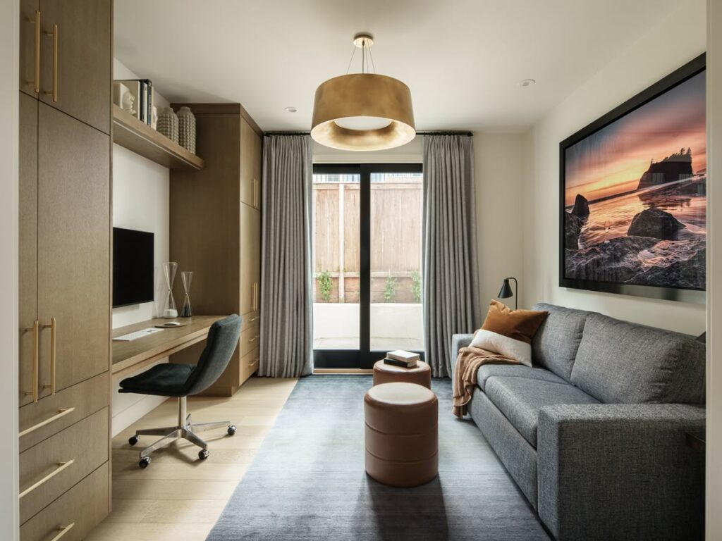 f998be2e8b198543cb0a6b44169ec777 Modern home office with a sleek desk, cozy gray sofa, stylish lighting, and large landscape artwork, creating a warm and inviting space. | Sky Rye Design Modern home office with a sleek desk, cozy gray sofa, stylish lighting, and large landscape artwork, creating a warm and inviting space.