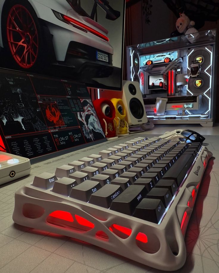 Custom mechanical keyboard with red backlighting on a gaming desk setup featuring car-themed decor and light-up PC case.