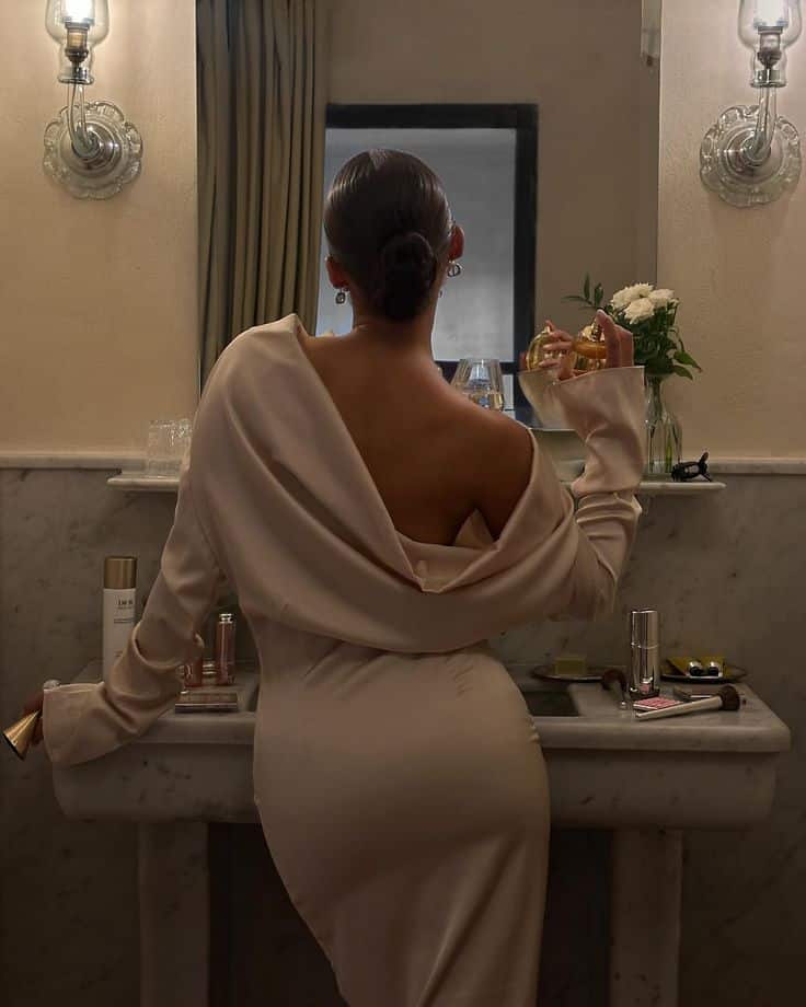 getting ready soaked in jadore __ _diorbeauty 🤍✨💫__diorbeauty diorbeautylovers Elegant woman in a backless dress holding a perfume bottle in a vintage-style bathroom near a marble vanity with beauty products. | Sky Rye Design Elegant woman in a backless dress holding a perfume bottle in a vintage-style bathroom near a marble vanity with beauty products.