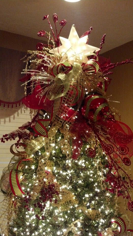 Elegant Christmas tree adorned with red and gold ornaments, a glowing star topper, and sparkling lights for festive holiday decor.
