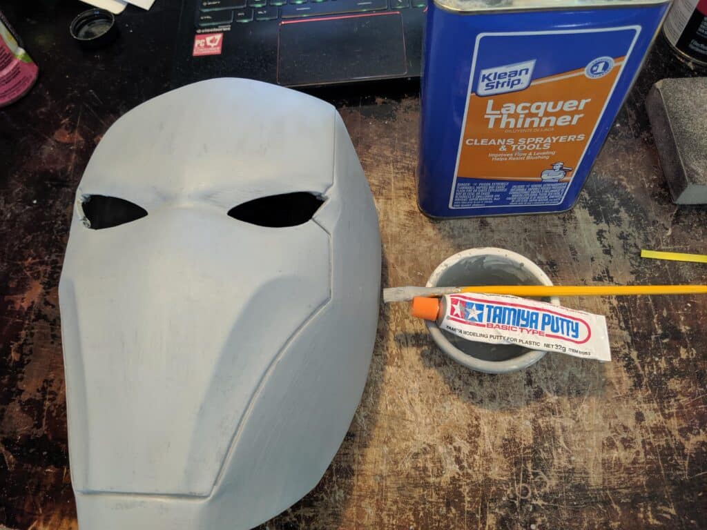 jpcawn61xso31 Gray helmet in progress with lacquer thinner and Tamiya putty on a workstation table. | Sky Rye Design Gray helmet in progress with lacquer thinner and Tamiya putty on a workstation table.