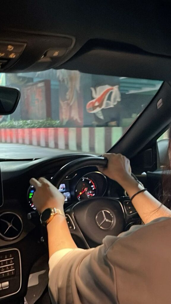 Person driving a Mercedes-Benz car, focusing on the road ahead. Steering wheel and dashboard visible, suggesting a nighttime drive.