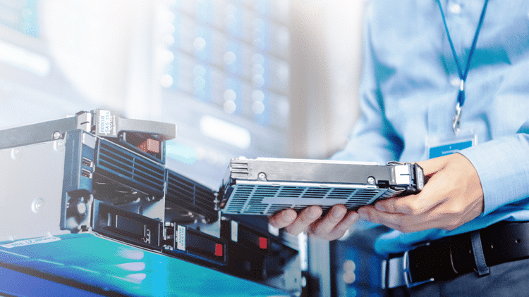 Person replacing a server hard drive in a data center, showcasing IT maintenance and technology management.