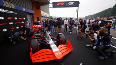 Photographers capture an Audi F1 car at a Formula 1 event, showcasing the sleek design and vibrant colors on display.