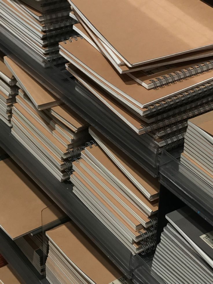 Stacks of brown spiral notebooks on shelves in a store, ready for purchase. Ideal for office, school, or personal use.