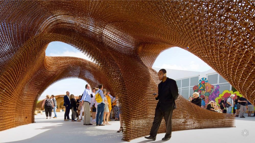 robotic-3d-printing-system-builds-large-lightweight-structures-in-free-space-1616462329 Sculptural wooden structure with people exploring the art installation at an outdoor event under blue skies. | Sky Rye Design Sculptural wooden structure with people exploring the art installation at an outdoor event under blue skies.