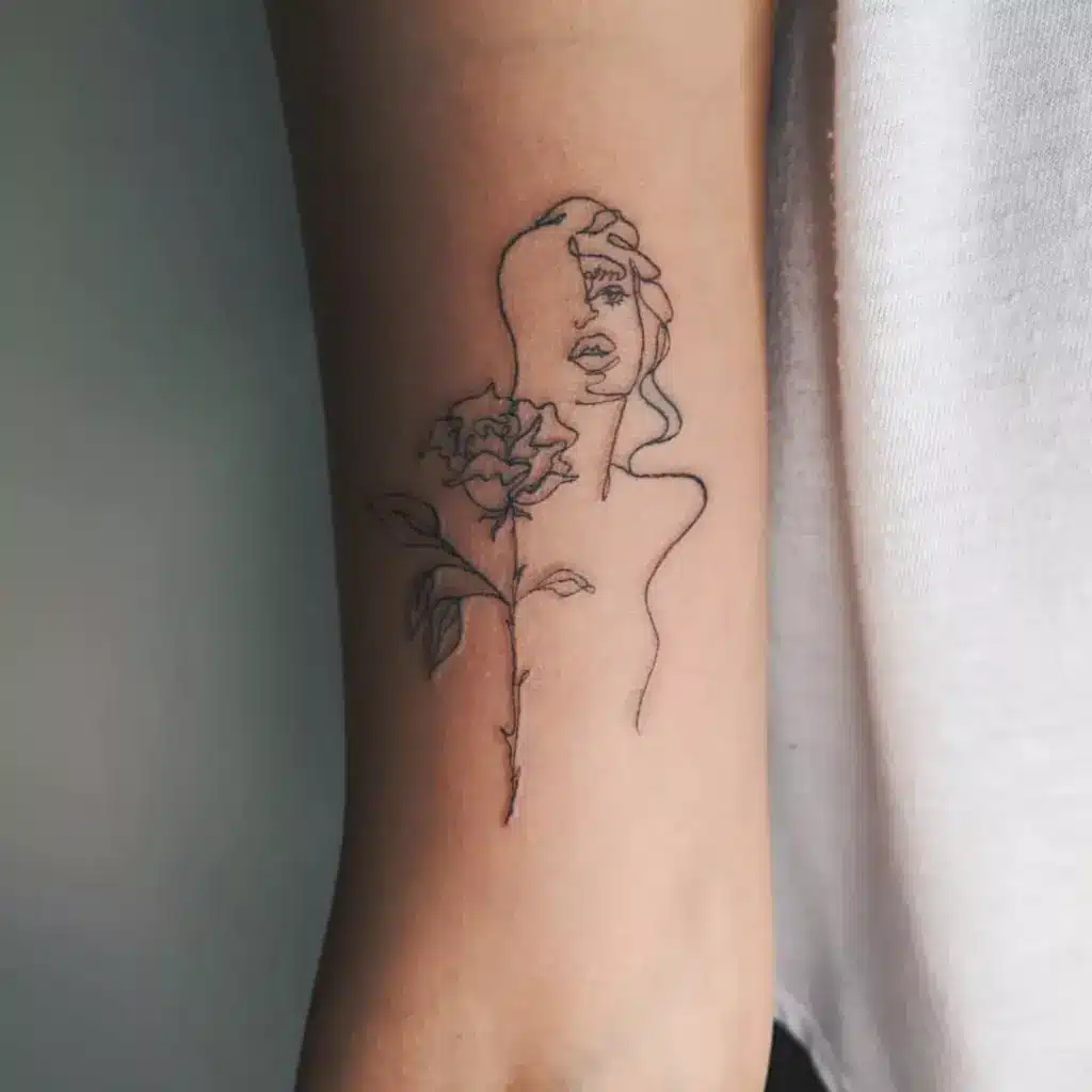 roseportrait-52b7ba23370d437e837d912d512eed49 Abstract line art tattoo of a woman's face with a blooming rose on an arm, showcasing minimalist design and fine line detailing. | Sky Rye Design Abstract line art tattoo of a woman's face with a blooming rose on an arm, showcasing minimalist design and fine line detailing.