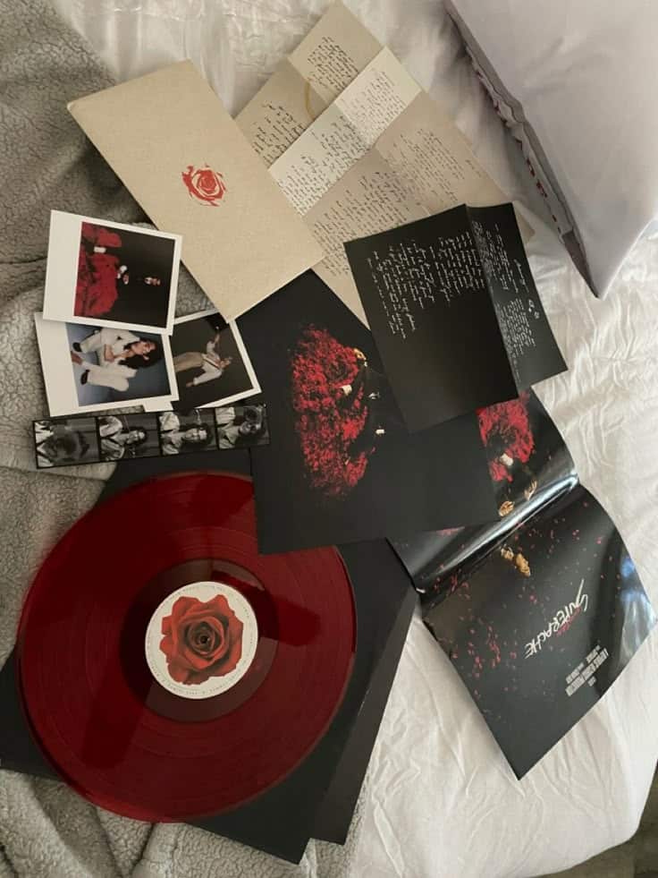 superache vinyl Red vinyl record with rose emblem, surrounded by handwritten letters and photos, displayed on a bed. Album art with theme of roses. | Sky Rye Design Red vinyl record with rose emblem, surrounded by handwritten letters and photos, displayed on a bed. Album art with theme of roses.