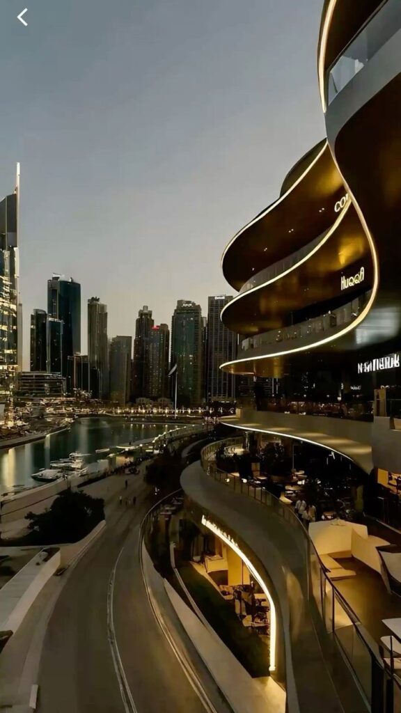 the city I live in xo Modern waterfront architecture with illuminated balconies at dusk, overlooking a city skyline and marina. | Sky Rye Design Modern waterfront architecture with illuminated balconies at dusk, overlooking a city skyline and marina.