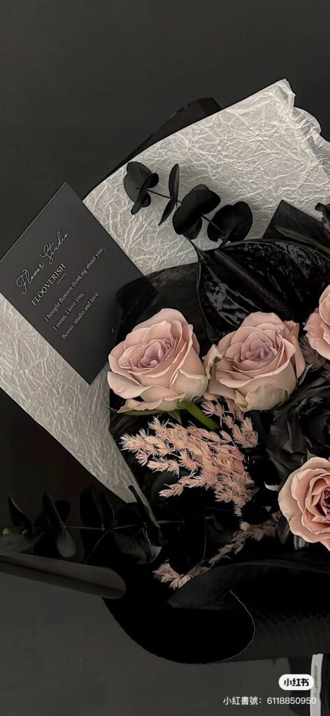 undefined 1 Elegant bouquet with pink roses, black leaves, and a decorative card on crumpled white paper. | Sky Rye Design Elegant bouquet with pink roses, black leaves, and a decorative card on crumpled white paper.