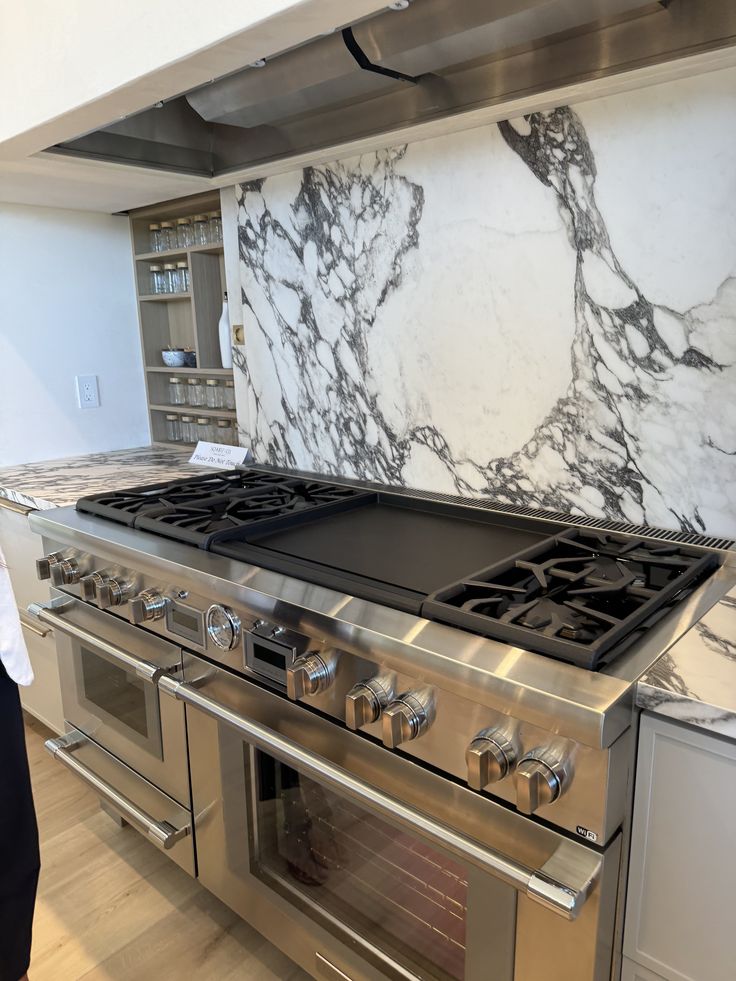 Luxury stainless steel kitchen range with marble backsplash and multiple burners. Perfect for modern cooking spaces.