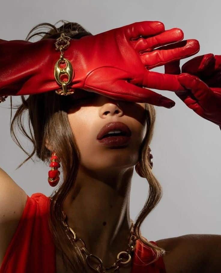 Fashion portrait with red gloves and jewelry, highlighting bold lipstick and earrings. Elegant and stylish look.