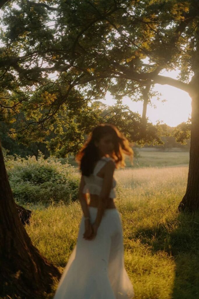 Woman in white dress in sunlit forest glade, soft focus, golden hour glow.