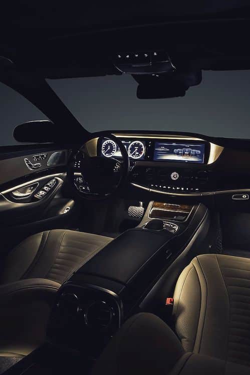 Luxury car interior with illuminated dashboard and leather seats, highlighting modern design and technology features.