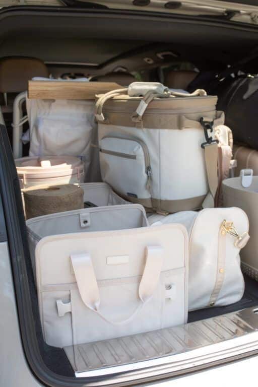 Organized car trunk with neatly stacked storage bags, coolers, and containers for efficient road trip packing.