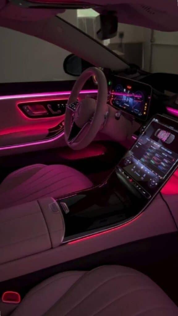 Luxury car interior with neon pink ambient lighting, featuring a high-tech dashboard and touchscreen display.