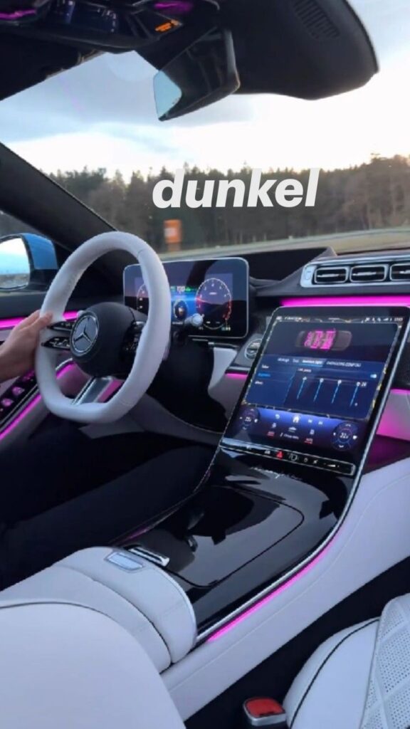 Luxury car interior with LED ambient lighting, digital dashboard, and sleek design on a scenic drive.