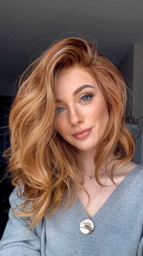 _ Woman with long, wavy red hair and blue eyes smiling, wearing a gray sweater indoors. | Sky Rye Design Woman with long, wavy red hair and blue eyes smiling, wearing a gray sweater indoors.