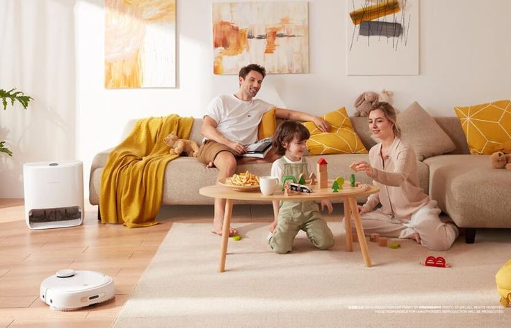 Family enjoying a cozy living room with a smart robot vacuum, playing games on the carpeted floor, surrounded by warm yellow decor.