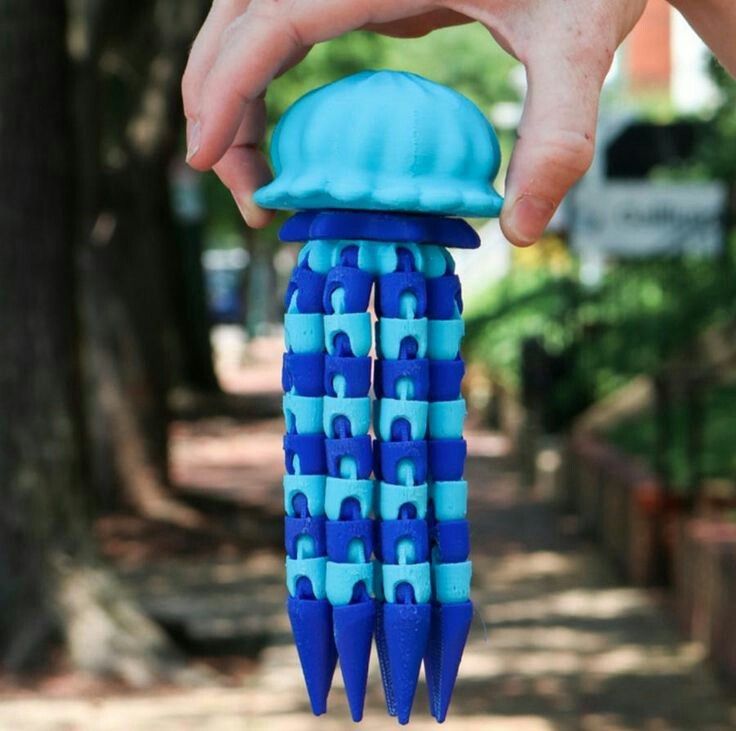 3D printed blue and turquoise jellyfish toy held in hand, showcasing flexible tentacle design.
