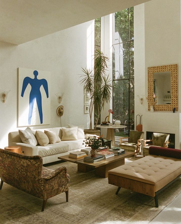 Screenshot Stylish living room with modern furniture, large windows, and abstract blue artwork. Cozy and elegant interior design. | Sky Rye Design Stylish living room with modern furniture, large windows, and abstract blue artwork. Cozy and elegant interior design.