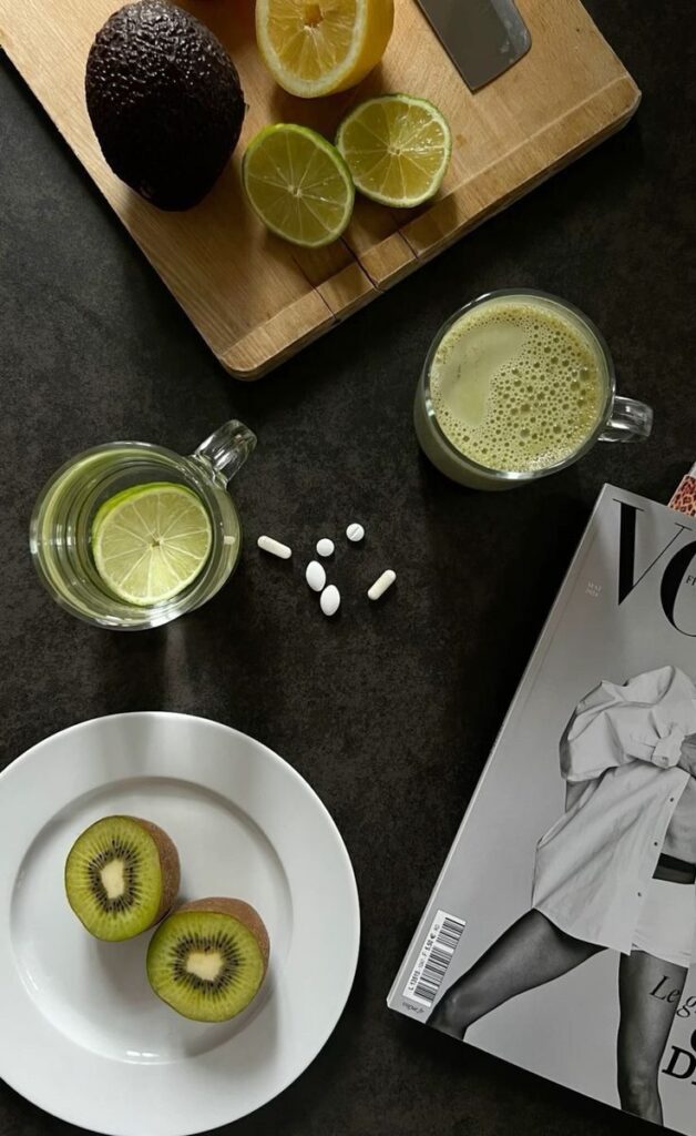 _ Avocado, lemon, kiwi, supplements, green drink, lime water, magazine on dark surface. Healthy lifestyle concept. | Sky Rye Design Avocado, lemon, kiwi, supplements, green drink, lime water, magazine on dark surface. Healthy lifestyle concept.