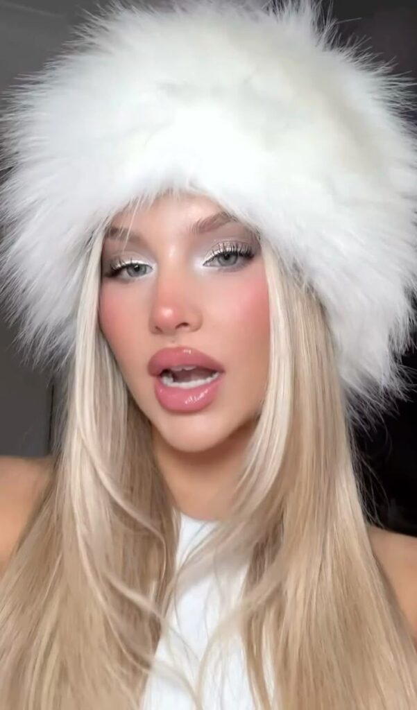 Woman wearing a stylish white fur hat and white top, blonde hair, and glam makeup. Winter fashion and beauty close-up portrait.