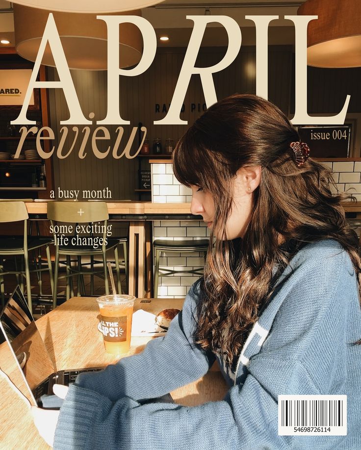Young woman with long hair working on a laptop in a cozy cafe, featured in a magazine cover titled April Review: A Busy Month.