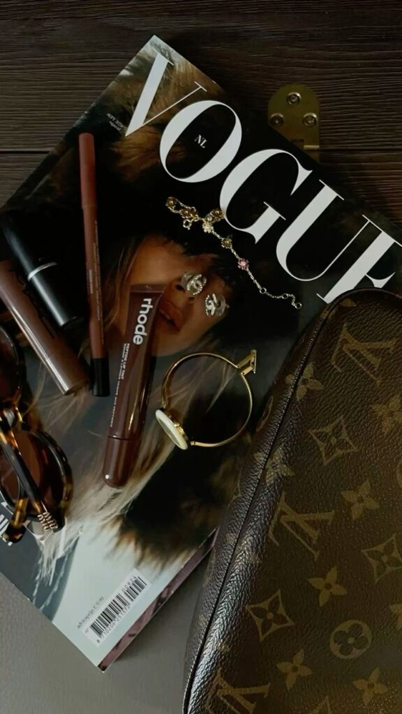 zdgfbdf Fashion magazine with makeup, jewelry, and luxury bag on a wooden surface. | Sky Rye Design Fashion magazine with makeup, jewelry, and luxury bag on a wooden surface.