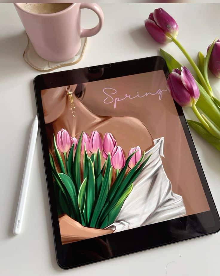 Тюльпаны 💐 Tablet displaying spring artwork with tulips, next to a cup and fresh tulips on a table. | Sky Rye Design Tablet displaying spring artwork with tulips, next to a cup and fresh tulips on a table.