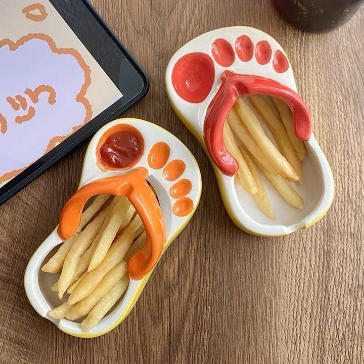 авиыа Novelty sandal-shaped plates with fries and ketchup, placed on a wooden table for a creative dining experience. | Sky Rye Design Novelty sandal-shaped plates with fries and ketchup, placed on a wooden table for a creative dining experience.