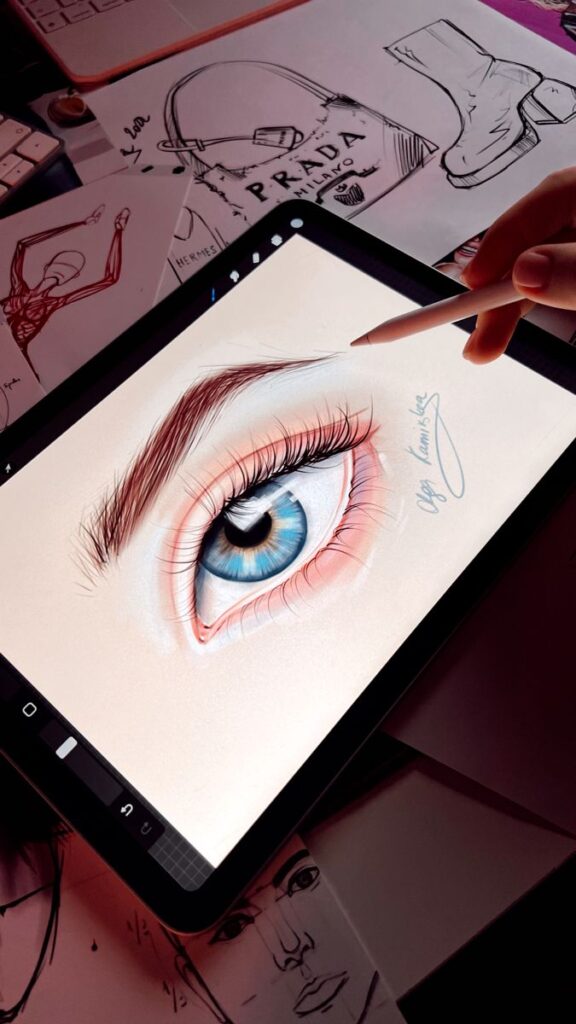 екрифуп Digital drawing of a detailed blue eye on a tablet with sketches in the background. | Sky Rye Design Digital drawing of a detailed blue eye on a tablet with sketches in the background.