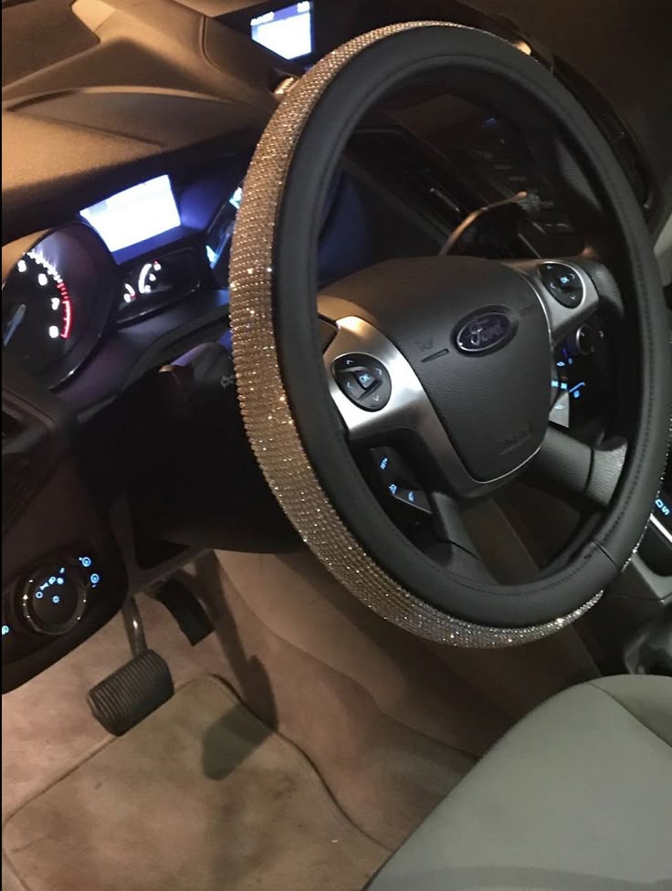 Luxury car interior with a sparkling, rhinestone steering wheel cover on a Ford model, featuring illuminated dashboard.