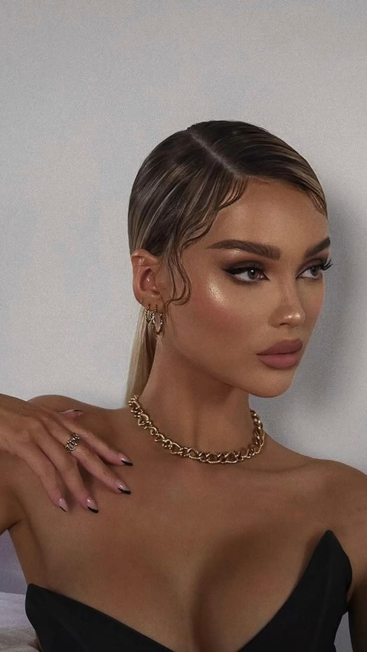 Elegant woman with sleek hairstyle, wearing gold jewelry and stylish black outfit. Glamorous makeup accentuates her look.