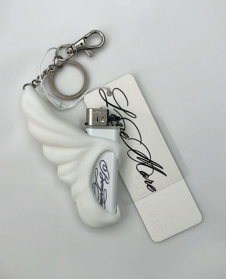 ✨FOLLOW_SAVE FOR MORE White wing-shaped lighter with keychain clip, black script text, and USB port on a minimal background for modern and stylish accessory appeal. | Sky Rye Design White wing-shaped lighter with keychain clip, black script text, and USB port on a minimal background for modern and stylish accessory appeal.